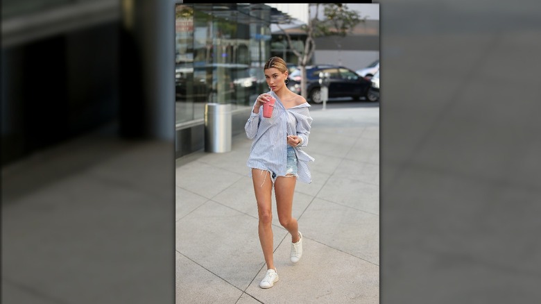 Hailey Bieber wearing oversized button-down and jean shorts 