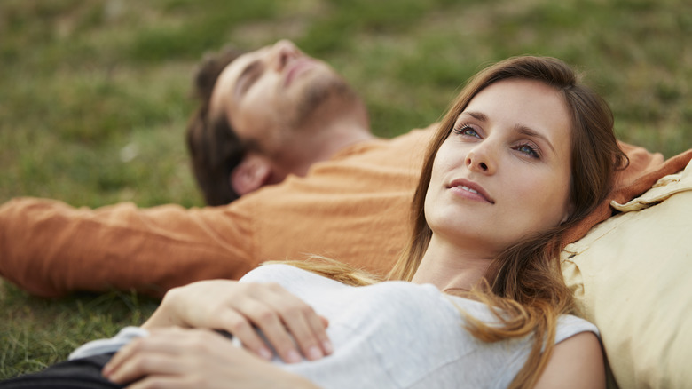 Woman lying on man's stomach on grass