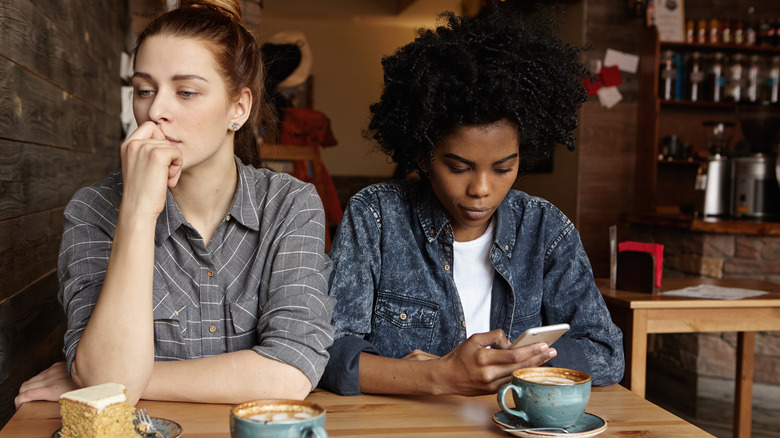 two women looking distracted in coffee shop