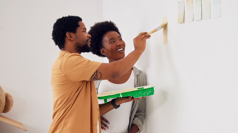 A couple painting their house while smiling 