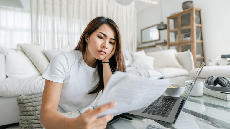 Woman looking stressed holding bills