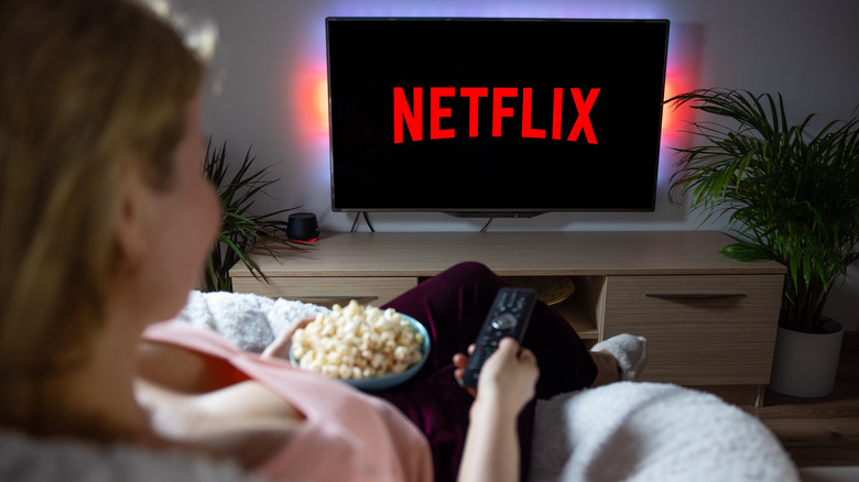 Woman with popcorn watching Netflix on television