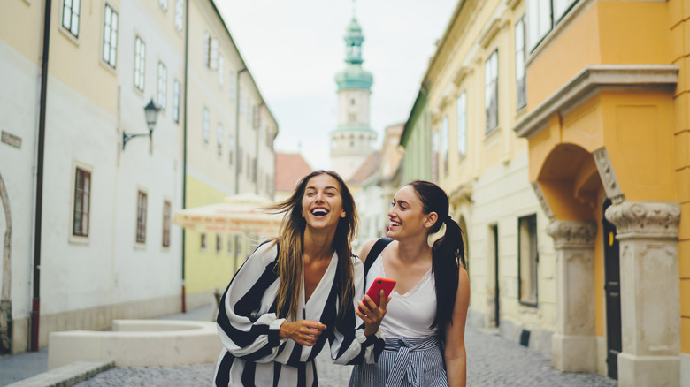 Two female friends laughing in European city 