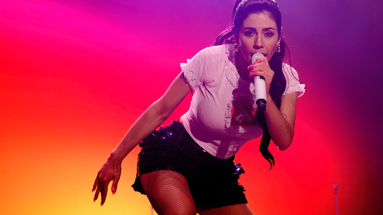 MARINA performing with a microphone in hand