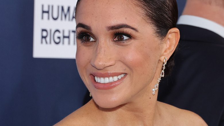 Meghan, Duchess of Sussex smiles at a red carpet event