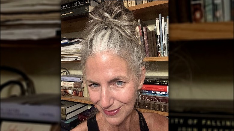 A gray haired woman with a messy bun 
