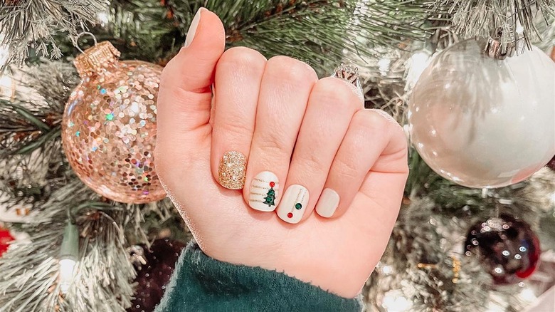 Short Christmas nails in front of a Christmas tree