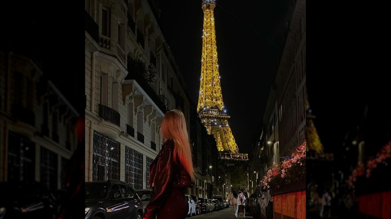 Woman standing next to Eiffel Tower