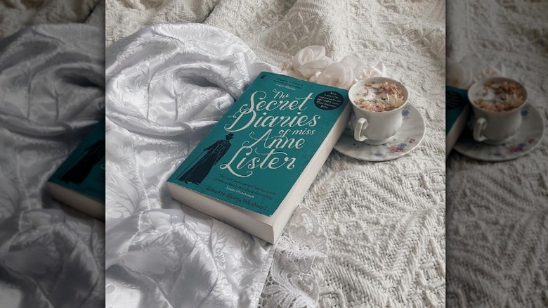 Book with cup of coffee on bed