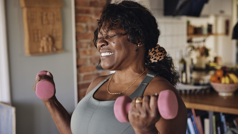 An older woman smiles while lifting dumbbells