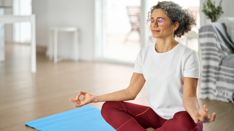 Older woman meditating in her living room