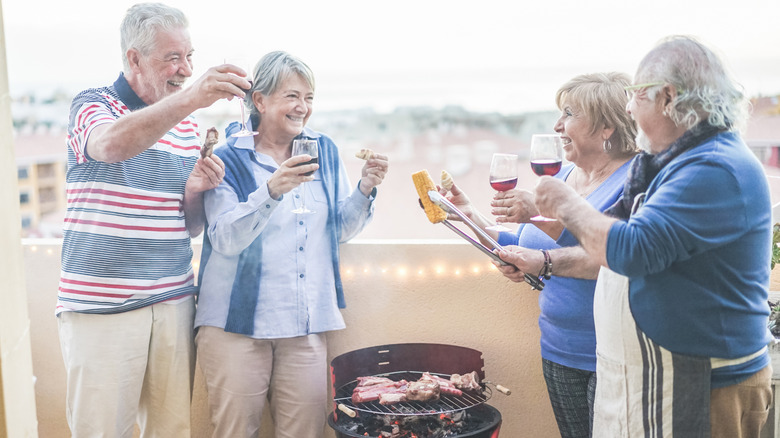 Two senior couples celebrate around a grill