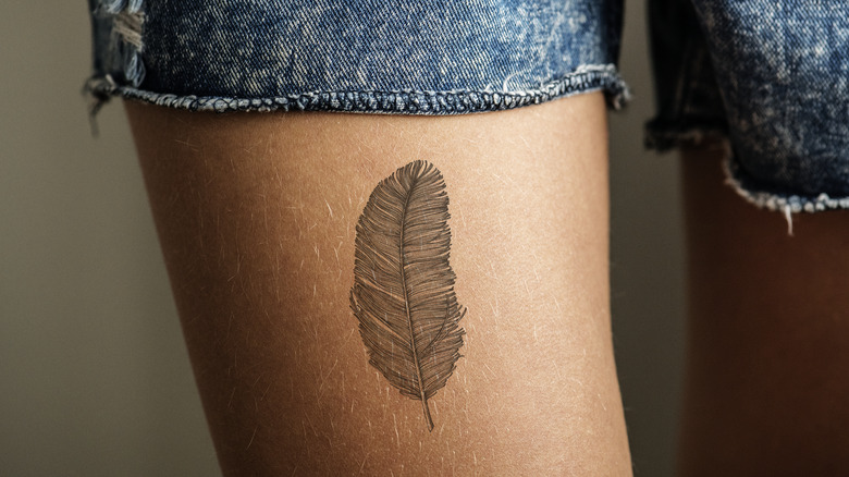 tattoo of feather on a woman's leg