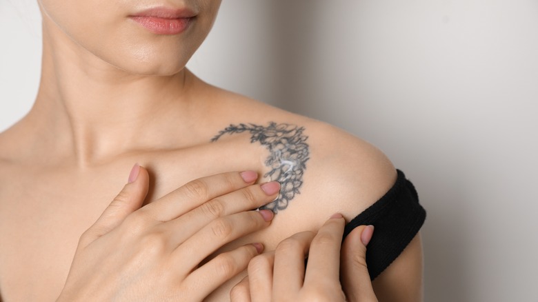 woman touching floral tattoo on her shoulder