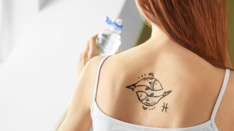 tattoo of pisces symbol on woman's back
