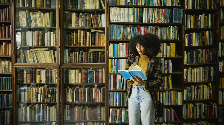 Woman reading against a bookshelf