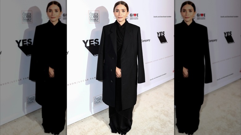 Ashley Olsen in a long black coat with a long skirt at an event