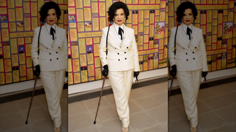 Bianca Jagger at an event in a white suit with a black bow tie