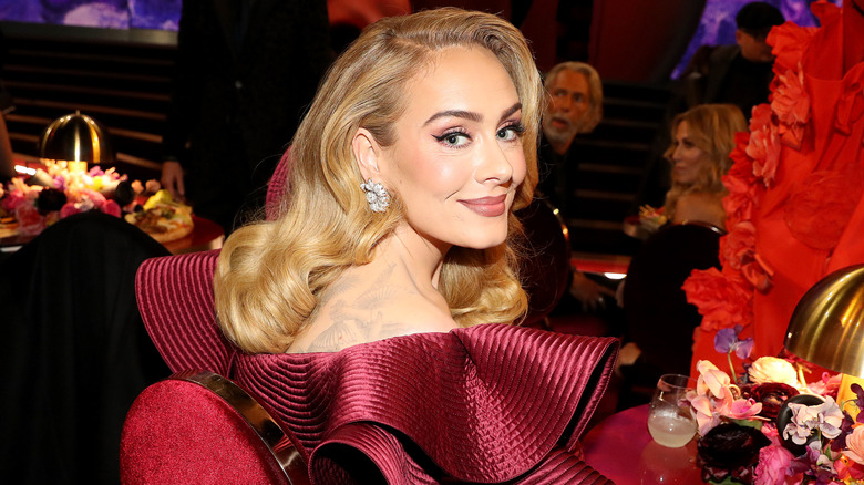 Adele at an awards show in a red gown with blonde, curled hair