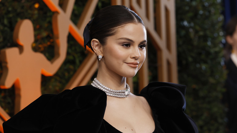 Selena Gomez smiling at the SAG Awards with her hair in a slicked back bun