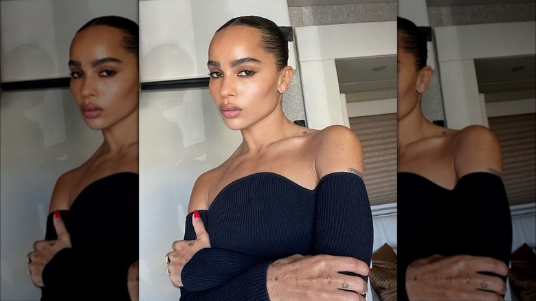 Zoe Kravitz with her hair pulled back, crossing her arms