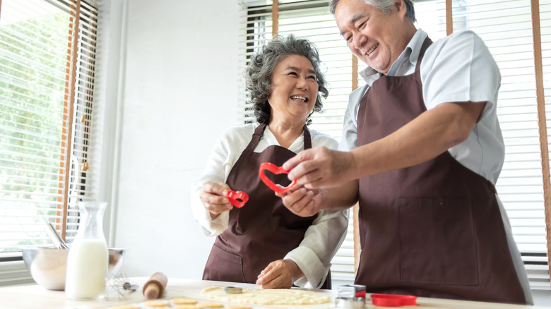 Older couple using heart shaped cookie cutters and smiling