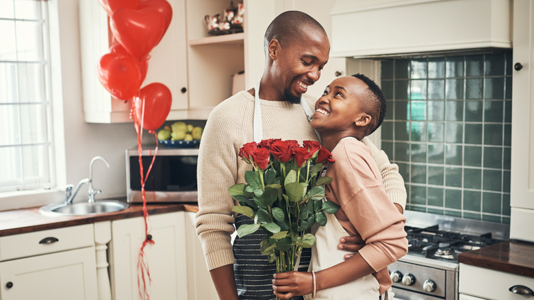 A couple embracing holding bouquet of roses