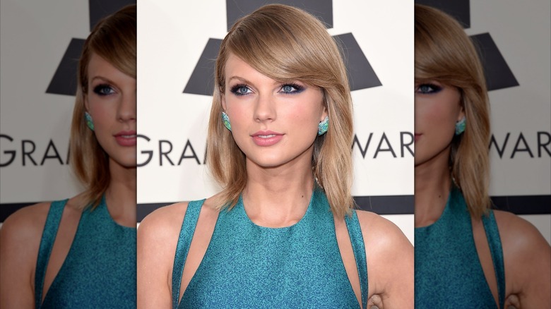 Taylor Swift looking off-camera with a small smile while wearing side-swept bangs and a straightened bob