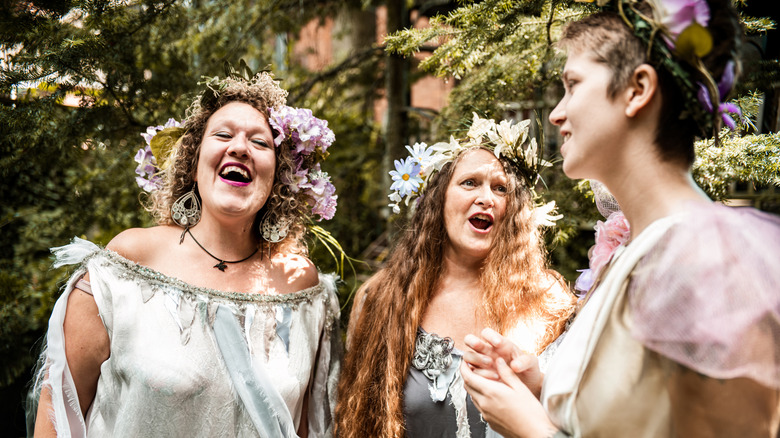 Three women laughing and talking together while dress in fairy and fantasy costumes