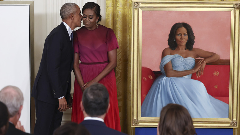 Michelle Obama standing with President Barack Obama next to her White House portrait