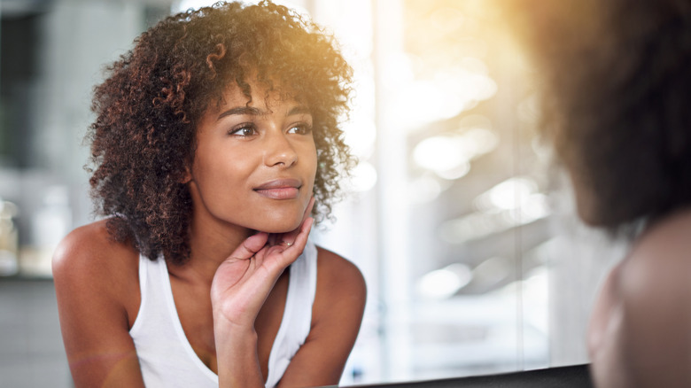 Woman looking at her skin in the mirror