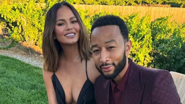 Chrissy Teigen posing with John Legend outside