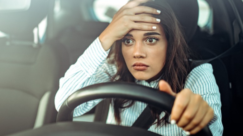 Woman overwhelmed in car, hand on forehead