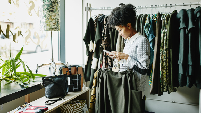 woman looking at phone while shopping at a boutique