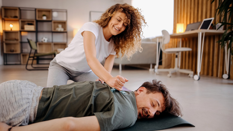 Woman giving massage to her partner on the floor