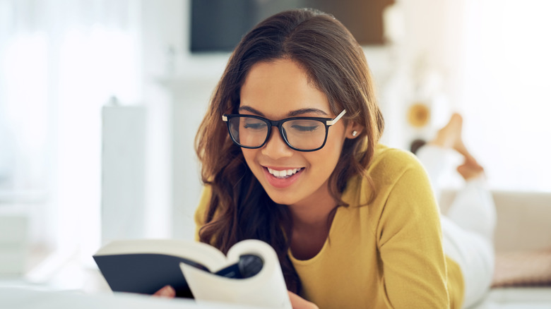 A woman smiling as she reads her book