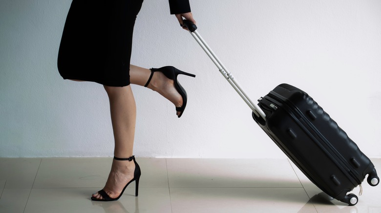 Woman in heels pulling a suitcase 