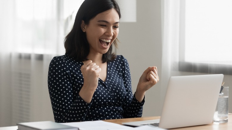 Woman excited looking at laptop