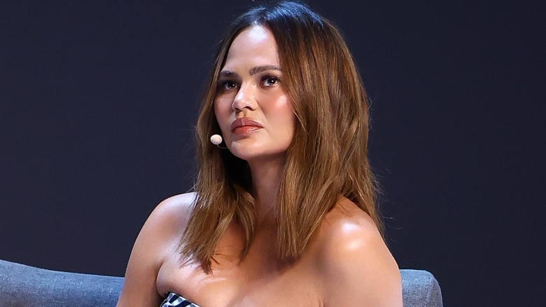 Chrissy Teigen wearing head microphone looking neutral