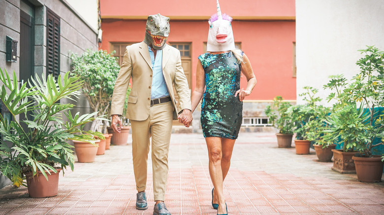 Two people holding hands and wearing full face masks