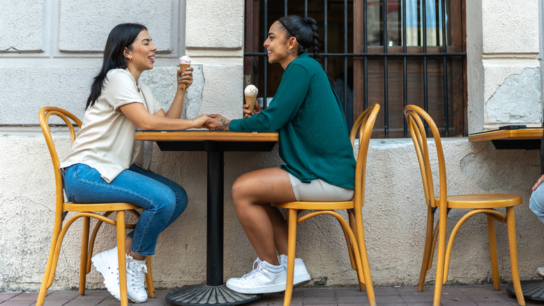 Two women sitting at table eating ice cream on a date