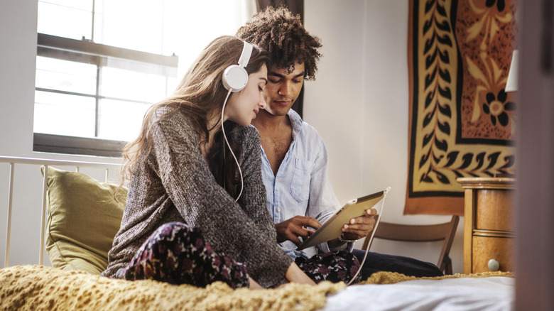 Woman and man listening to music in bed