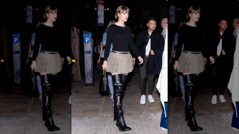 Taylor Swift walking in NYC, wearing a black sweater, pleated skirt, and thigh-high boots