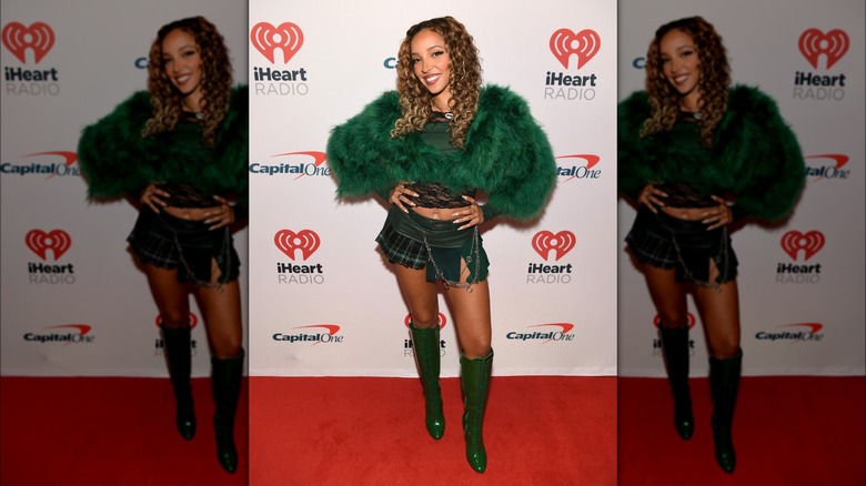 Tinashe posing at the iHeart Radio red carpet, wearing a micro mini-skirt with a cropped, faux fur jacket