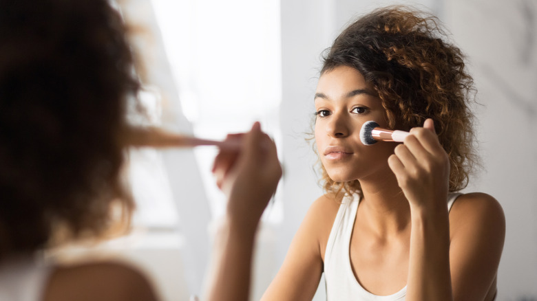 Young woman applying makeup 