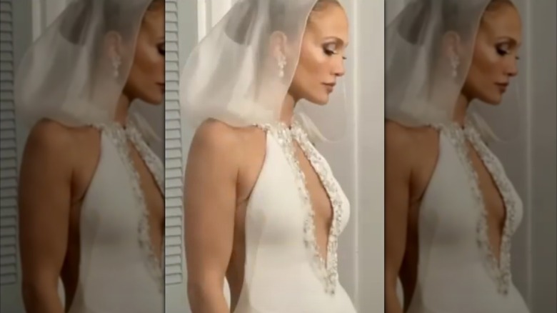 Jennifer Lopez wearing fitted, halter-neck wedding dress with a sheer hood veil