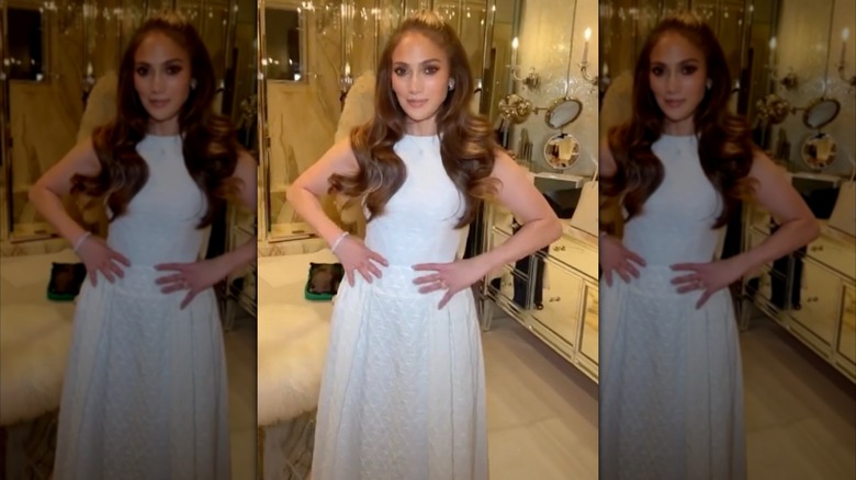 Jennifer Lopez in a hotel bathroom wearing a simple white wedding dress