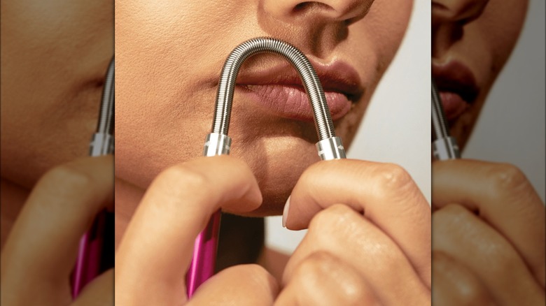 Woman using coil hair remover on upper lip