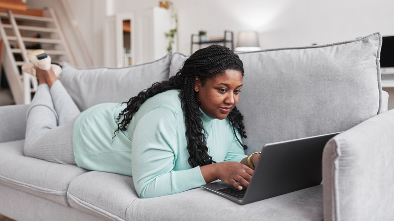 Woman online shopping lying on couch