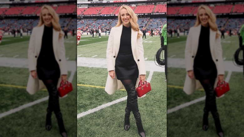 Brittany Mahomes in a black dress and white jacket with a red purse on Instagram